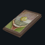 Tennis Racket with Ball Laying on Court Tri-fold Wallet<br><div class="desc">Enjoy a little tennis with this scene painted by Ethan Harper. A well stitched racket with a ball sitting on the middle,  you just want to pick it up,  head to your local court and play a game. Purchase your copy of this print today!</div>