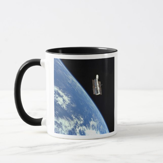 The Hubble Space Telescope with a blue earth Mug (Left)