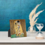 The Kiss by Gustav Klimt Plaque<br><div class="desc">The Kiss by Gustav Klimt The Kiss is an oil-on-canvas painting with added gold leaf, silver and platinum. by the Austrian Symbolist painter Gustav Klimt. It was painted at some point in 1907 and 1908, during the height of what scholars call his "Golden Period". Featuring shimmering gold tones, stylized forms,...</div>