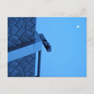 The moon hangs above the breakwater.  postcard