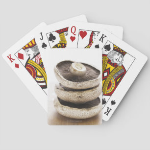 Three flat mushrooms in pile on wooden board playing cards
