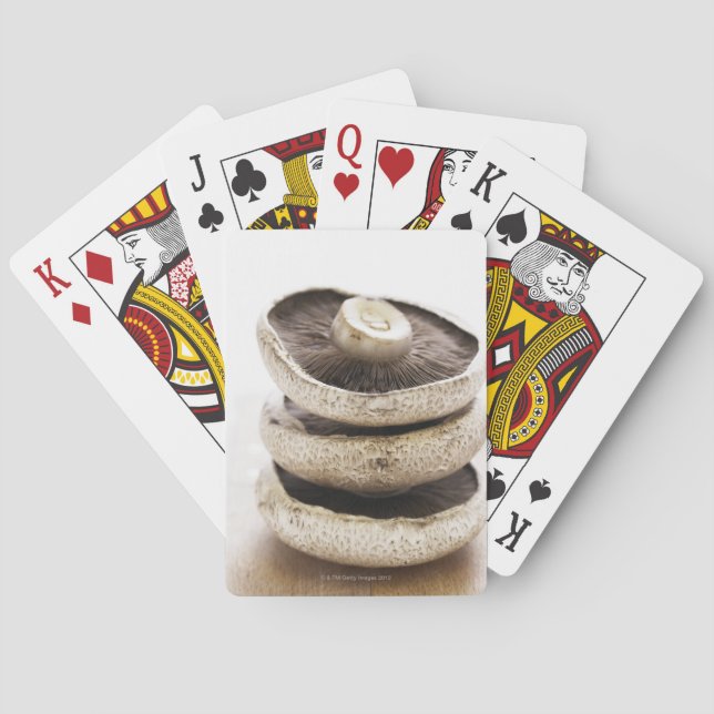 Three flat mushrooms in pile on wooden board playing cards (Back)