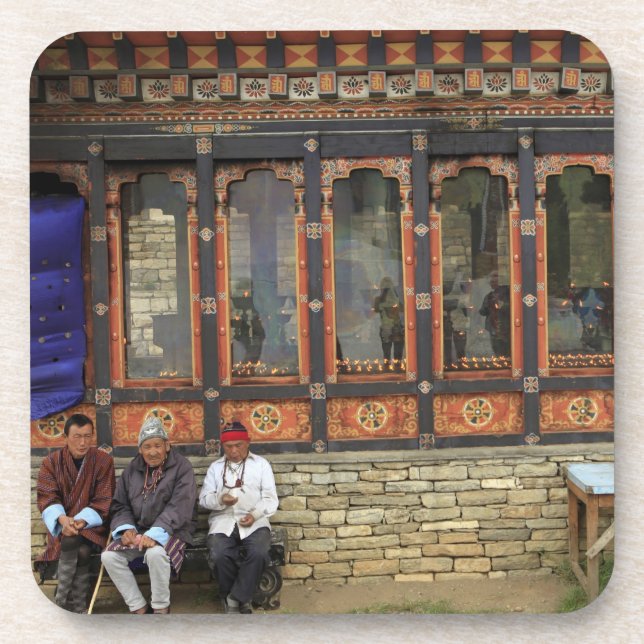 Three men sit on a bench at the Memorial Chorten Coaster (Front)
