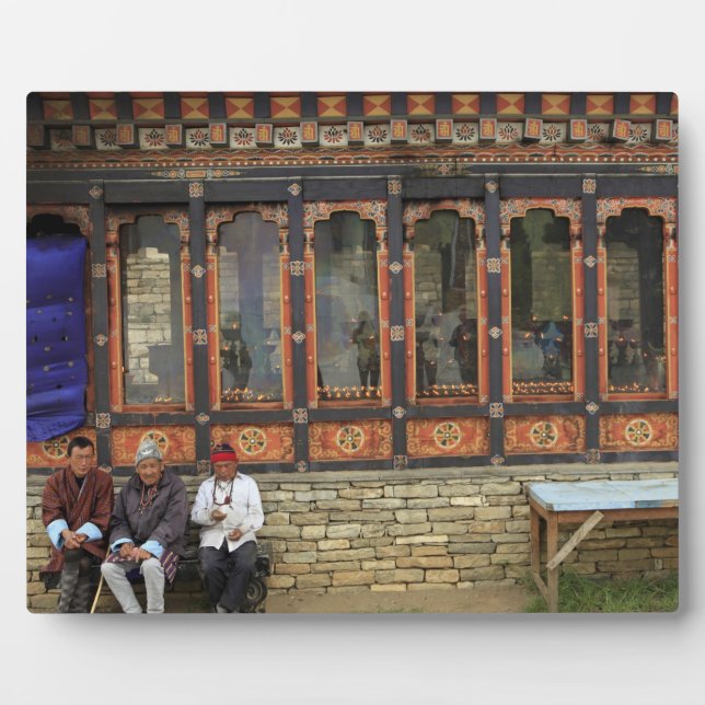 Three men sit on a bench at the Memorial Chorten Plaque (Front)