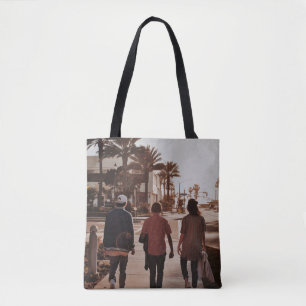 Three persons walking near palm trees tote bag