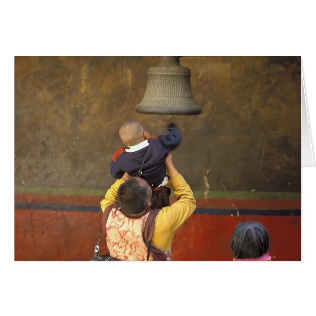 Tibetan Buddhist monk lifting a boy to ring a (Front Horizontal)