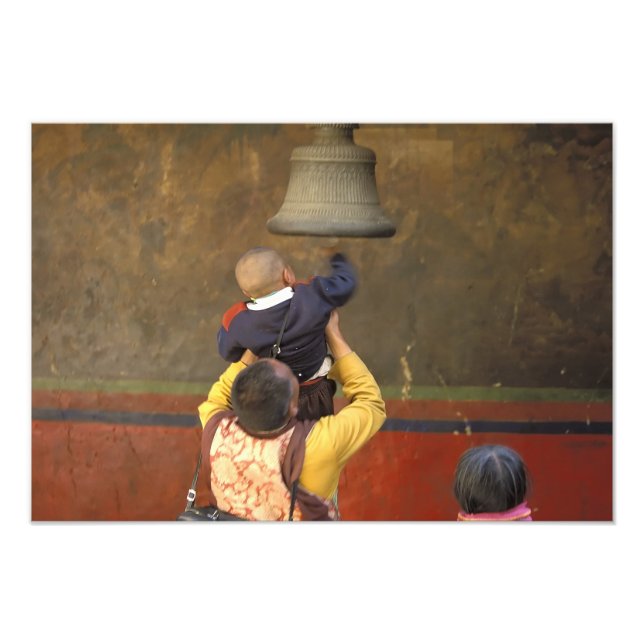 Tibetan Buddhist monk lifting a boy to ring a Photo Print (Front)