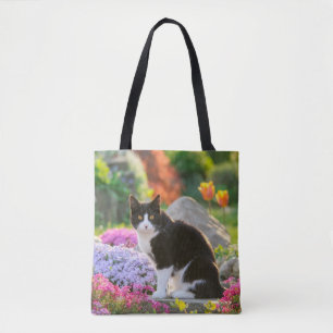 Tote Bag Un joli chat noir blanc dans un jardin fleuri colo
