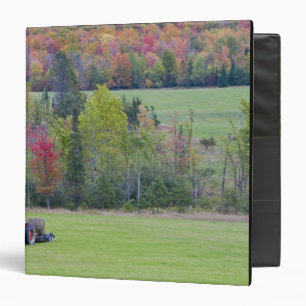 Tractor with hay bale in green field with binder