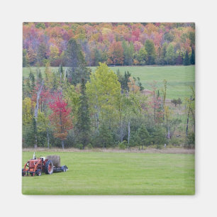 Tractor with hay bale in green field with magnet