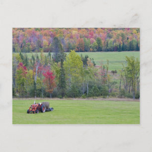 Tractor with hay bale in green field with postcard