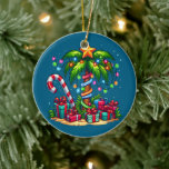 Tropical Christmas Palm Tree Ceramic Ornament<br><div class="desc">An ornament with a seasonal holiday image. A tropical palm tree decorated in festive lights with a star on top. A giant red and white candy cane sticking out of the sand. Christmas presents under the tree. Whimsical and fun.</div>