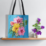 Tropical Flowers Blue Wood Personalized AOP Tote Bag<br><div class="desc">Personalized tote bag with big flowers design. All over print with pink and yellow hibiscus flowers. More little flowers and leaves make up this pretty design which has a background of blue wood grain. Include a name down the side of the front in elegant script font. This tote is lined...</div>