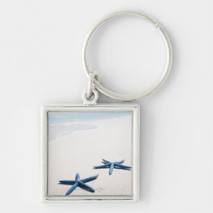 Two blue starfish at water's edge on tropical keychain