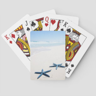 Two blue starfish at water's edge on tropical playing cards