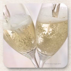 Two champagne flutes being filled with sparkling coaster