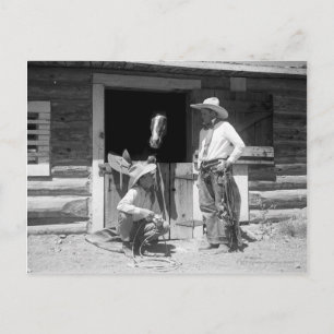 Two cowboys standing next to a barn with a horse postcard