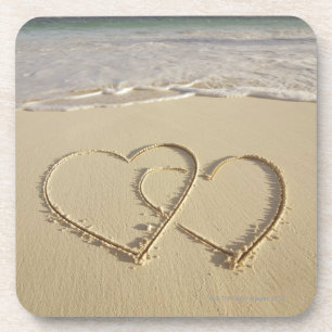 Two overlying hearts drawn on the beach with coaster