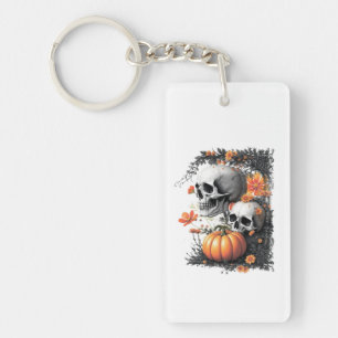 Two skulls and a pumpkin among flowers. keychain