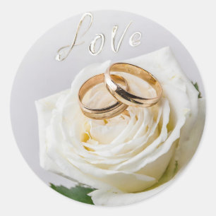Two wedding rings on a white rose classic round sticker