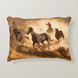 Two western cowboys riding horses, roping wild hor accent pillow