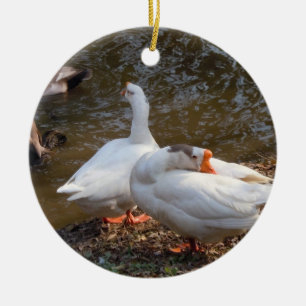 two white geese playing by a pond. ceramic ornament