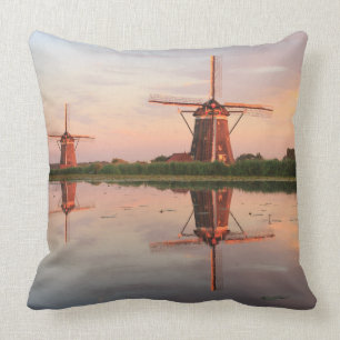 Two windmills with reflection at sunset throw pillow