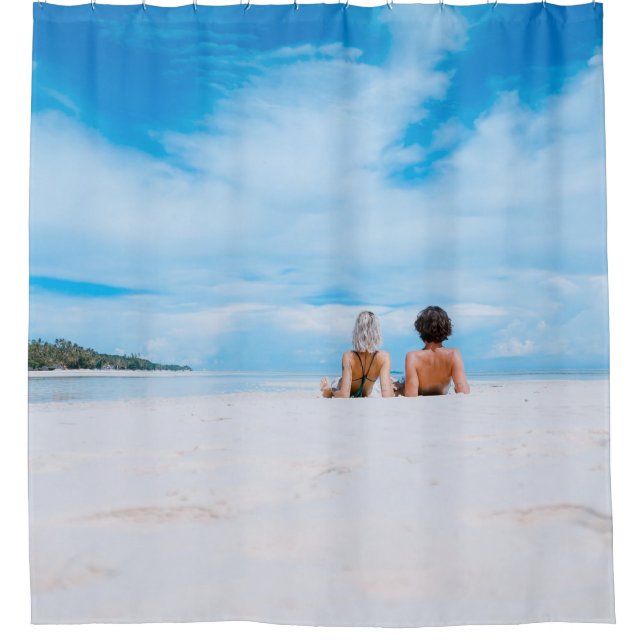 Two women lying on white sand facing beach under b (Front)