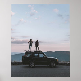 Two women standing on car's roof poster