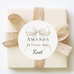 Tying the knot ivory bow pearls Bridal Shower Classic Round Sticker<br><div class="desc">Elevate your celebration with these chic bridal shower stickers. The design showcases a high-fidelity ivory,  cream colored bow intertwined with delicate pearl strands for a luxury finish. These labels are perfect for sealing bachelorette party invitation envelopes or adding to guest favor bags.</div>