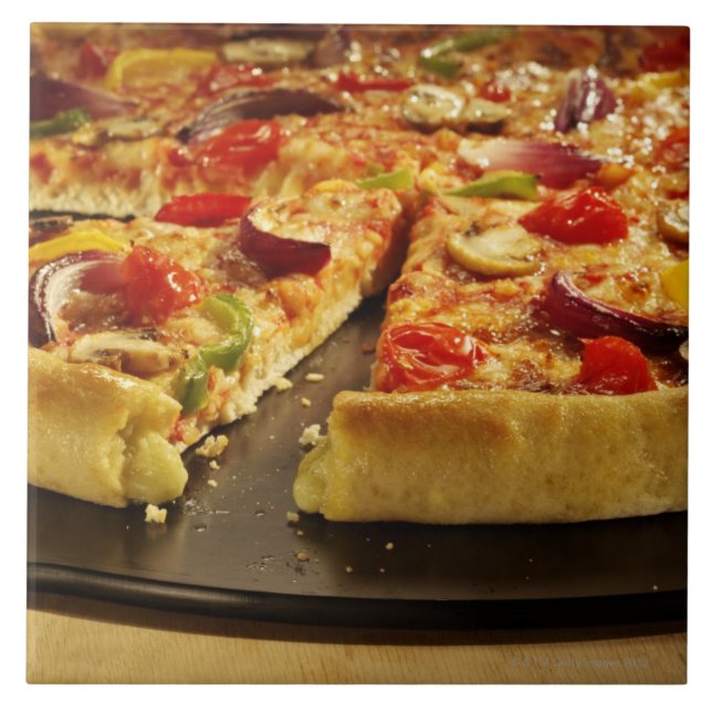 Vegetable pizza sliced on black pan on wood tile (Front)