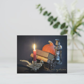 Vintage books and hourglass on dark table postcard