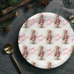 Vintage Nutcracker & Merry Christmas Paper Plate<br><div class="desc">A beautifully illustrated vintage-style Nutcracker soldier, resplendent in his classic attire, stands tall, holding a Merry Christmas banner. The rich, warm colours and intricate details evoke a sense of yuletide nostalgia, making it a perfect choice for those who appreciate the classic holiday aesthetics. May your holiday season be filled with...</div>