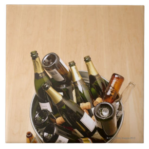 Waste bin full of empty champagne bottles on tile