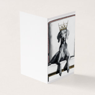 Weimaraner wearing a crown sitting on a chair 