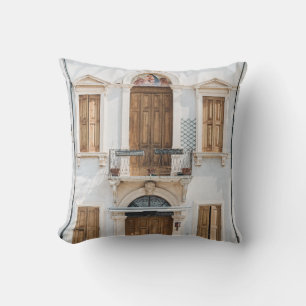 WHITE CONCRETE BUILDING WITH WOODEN DOORS AND WIND THROW PILLOW