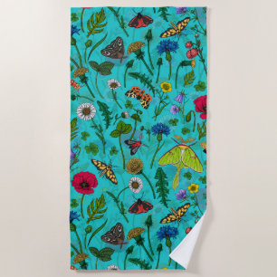Wild flowers and moths on teal beach towel