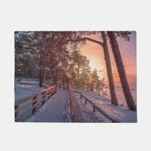 Winter sunset in pine forest near sea doormat