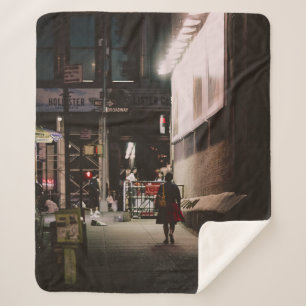 WOMAN IN BLACK AND RED DRESS WALKING BESIDE BROWN SHERPA BLANKET