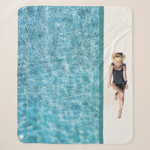 Woman in black bikini bottom and white sun hat sta sherpa blanket