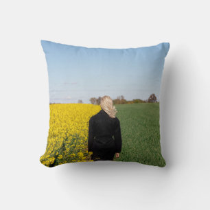 Woman in black coat standing on green grass field  throw pillow