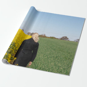 Woman in black coat standing on green grass field wrapping paper