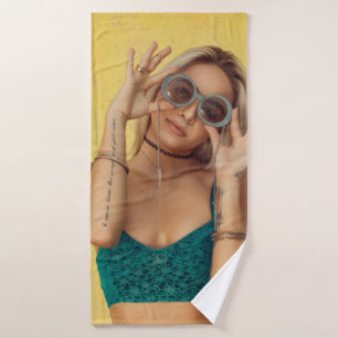 Woman in blue bralette holding sunglasses putting  bath towel