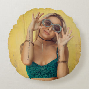 Woman in blue bralette holding sunglasses putting  round pillow