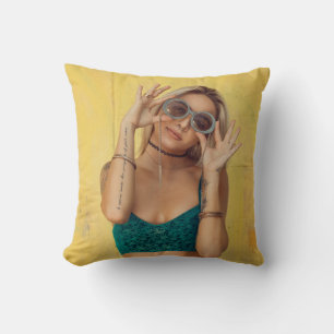 Woman in blue bralette holding sunglasses putting  throw pillow