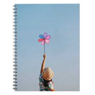 Woman in floral shirt and brown sun hat holding mu notebook
