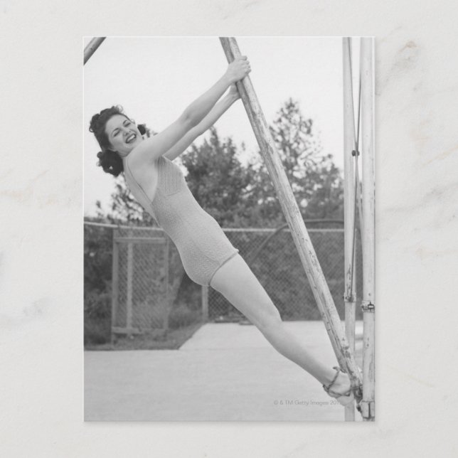 Woman in swimsuit hanging from wooden postcard (Front)