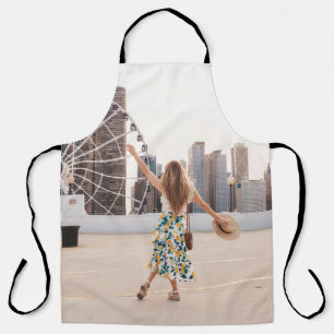 Woman in white and blue floral dress holding hat apron