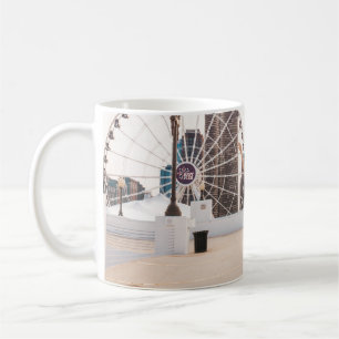 Woman in white and blue floral dress holding hat coffee mug