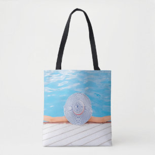Woman leaning on white concrete surface beside swi tote bag
